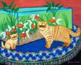 two orange tabby cats standing on a blue table cloth in front of a fish tank filled with gold fish.
